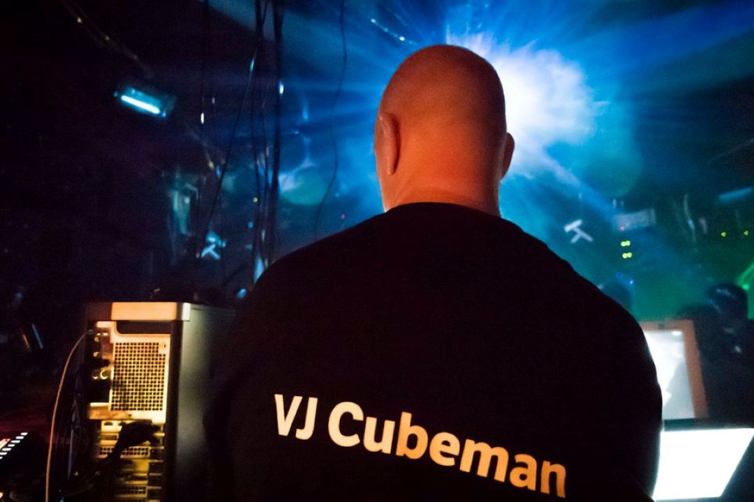 A shot of VJ Cubeman from behind, intent on his laptop